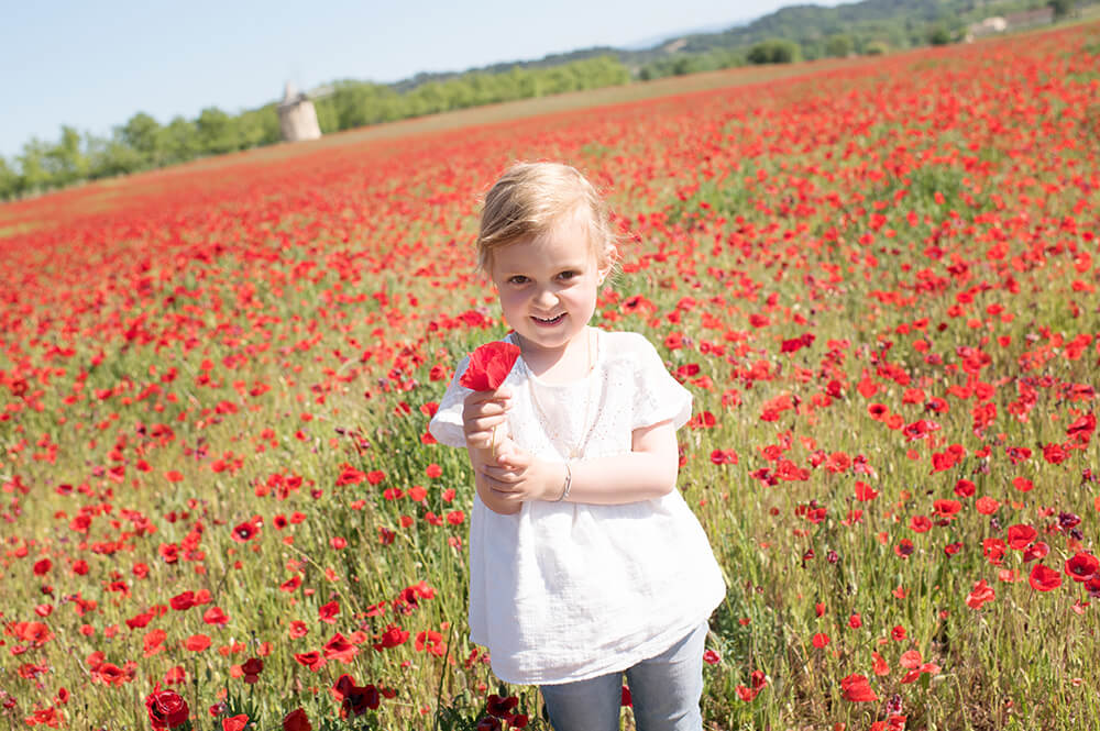 Portrait d'effané avec un coquelicot à la main.