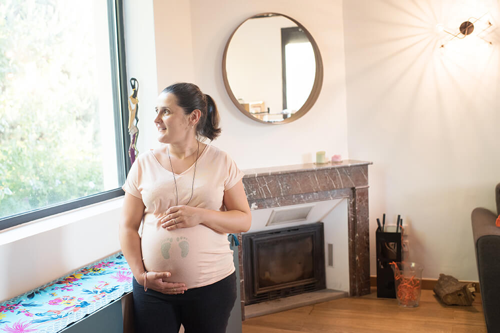 Jeune femme enceinte regardant par la fenêtre.