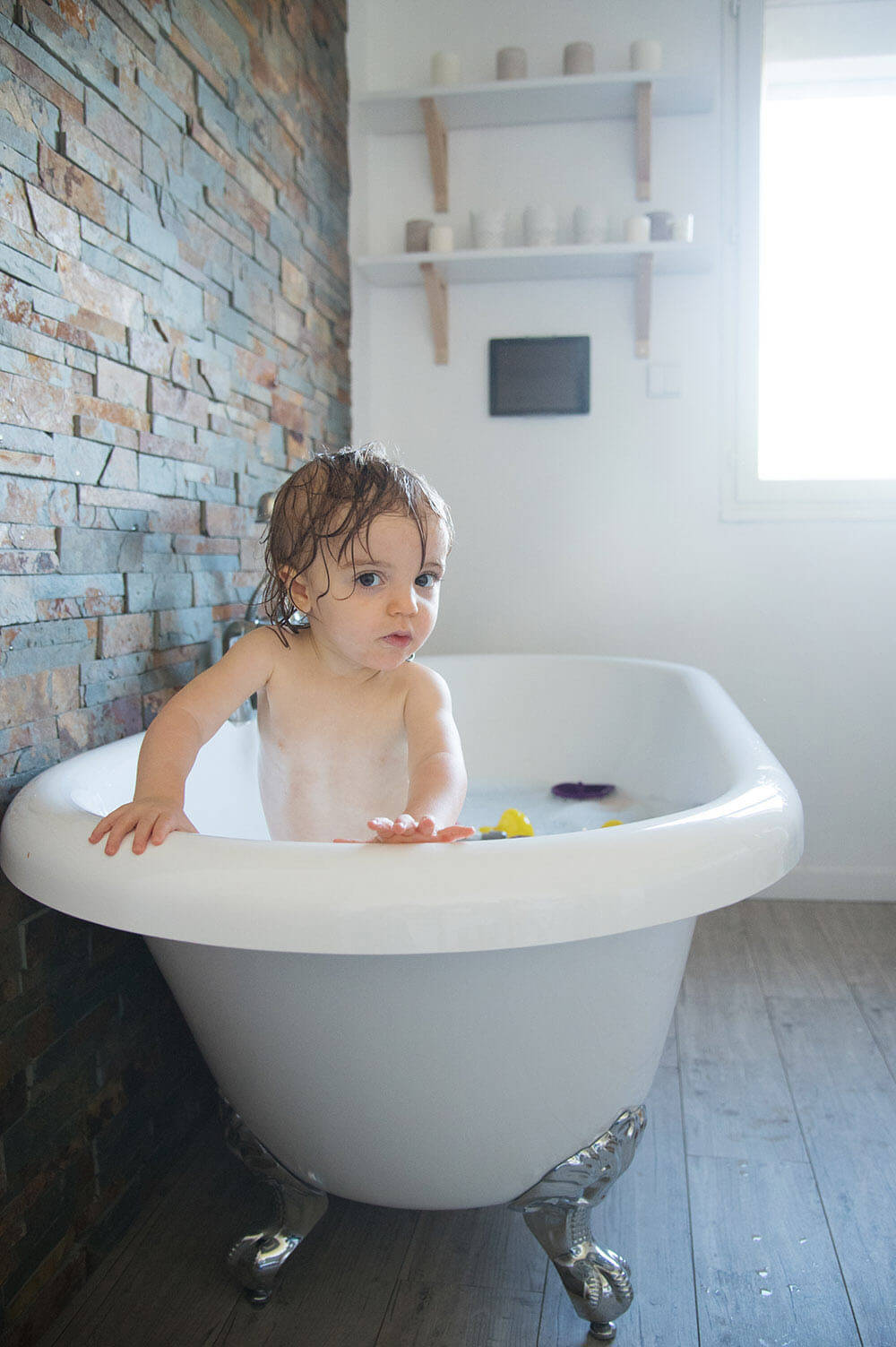 Portrait de bébé debout dans sa baignoire.