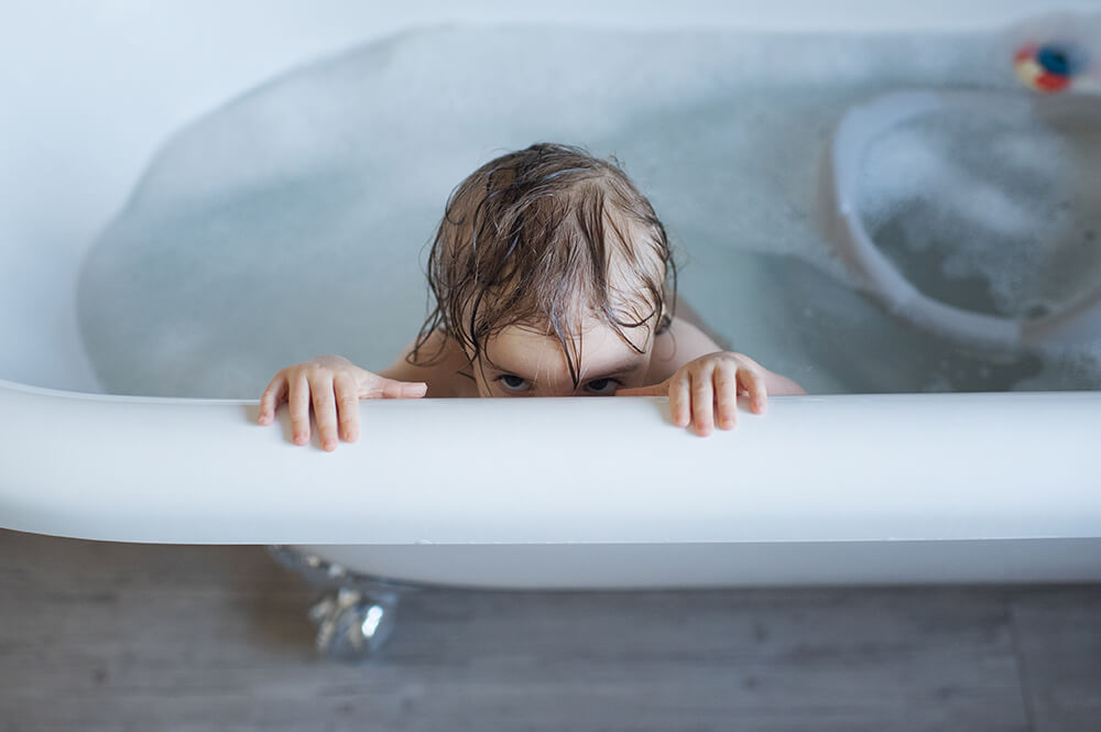 Portrait de bébé entrain de jouer dans son bain.