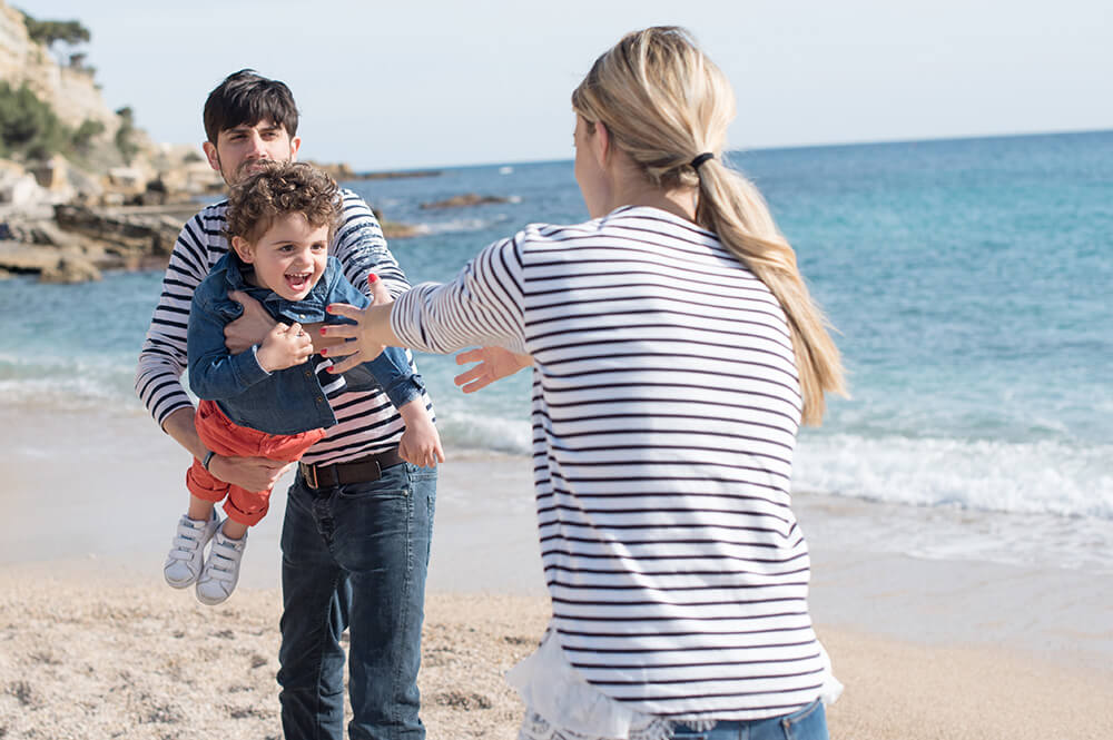 Parents qui jouent avec son enfant sur la plage.