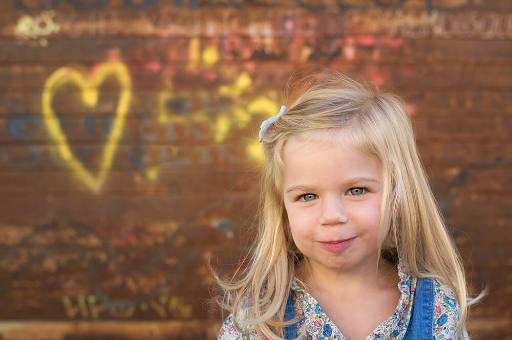 Portrait de gamin devant mur graffitis.