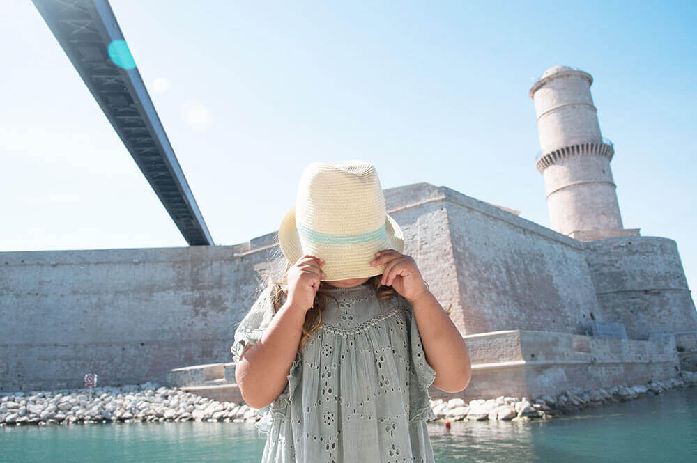 Photo d'une enfant avec un chapeau de paille devant le Fort Saint Jean.