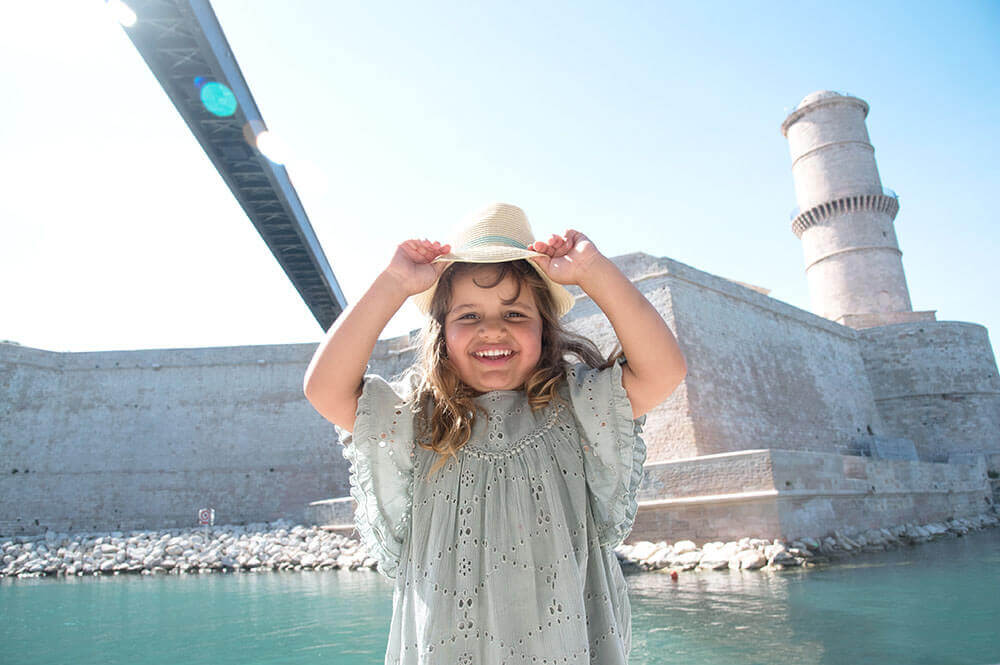Photo d'une enfant avec un chapeau de paille devant le Fort Saint Jean.