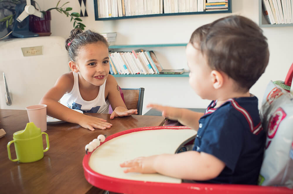 Moment de vie, à table, entre une sœur et son petit frère.