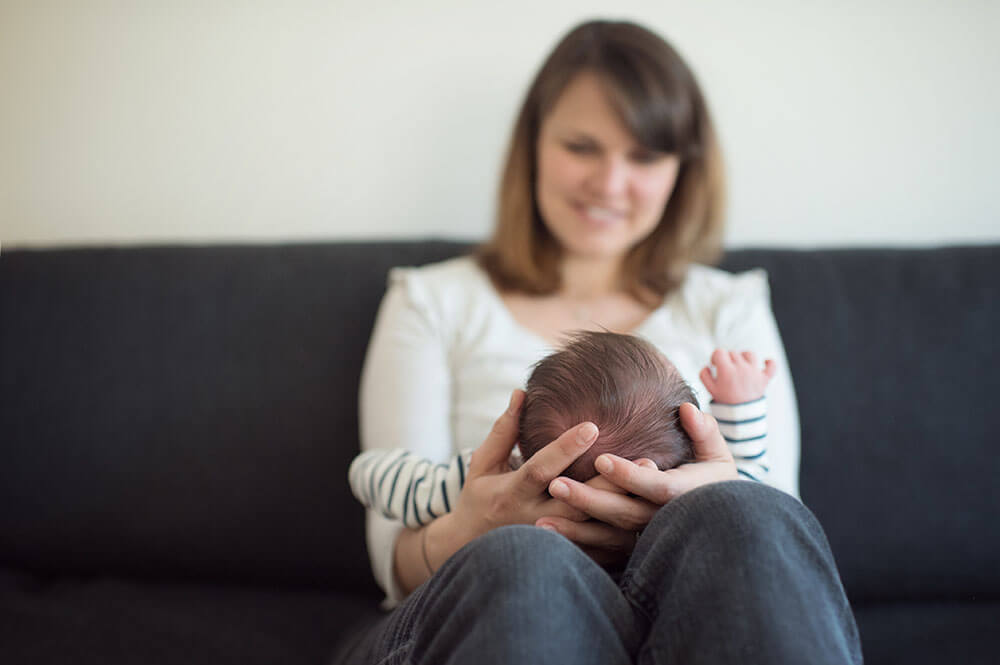 Petite tête de nouveau-né dans les mains de maman.