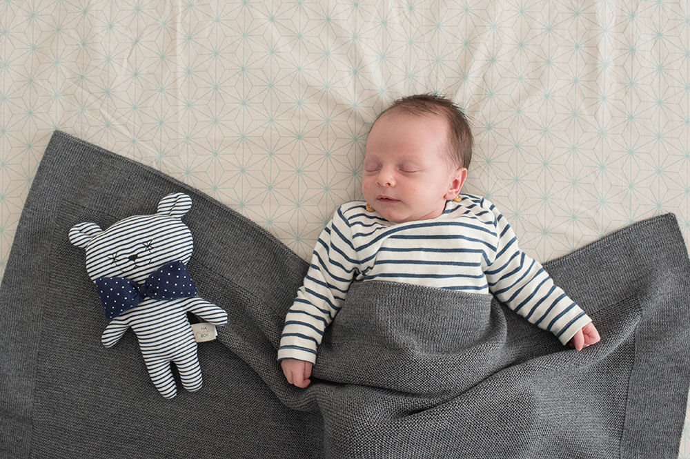 Baby avec son doudou. Tous les deux habillés avec des rayures bleues.