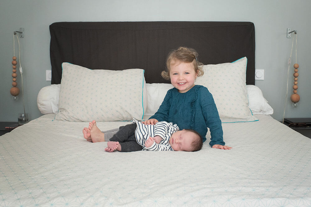 Sieste de bébé à côté de sa grande sœur très souriante.