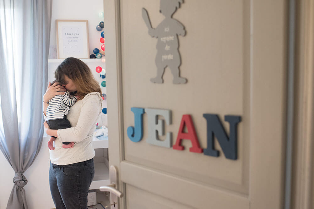 Portrait de bébé niché dans le cou de sa maman.