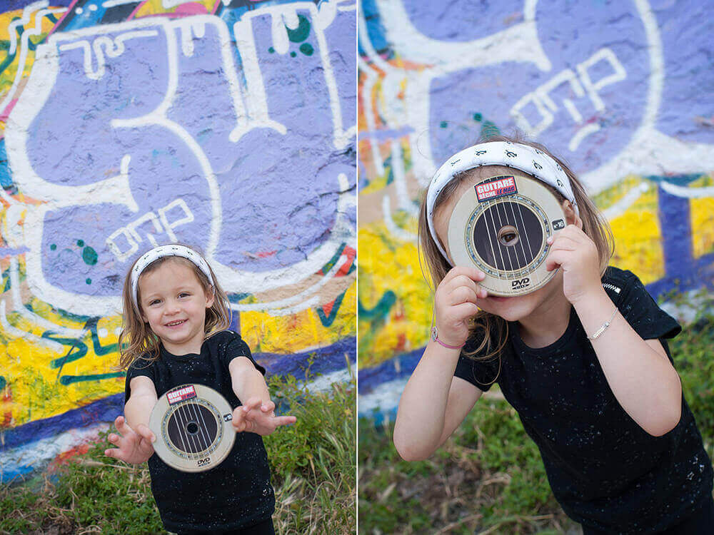 Portrait d'enfant entrain de jouer avec un CD devant un mur de graffitis