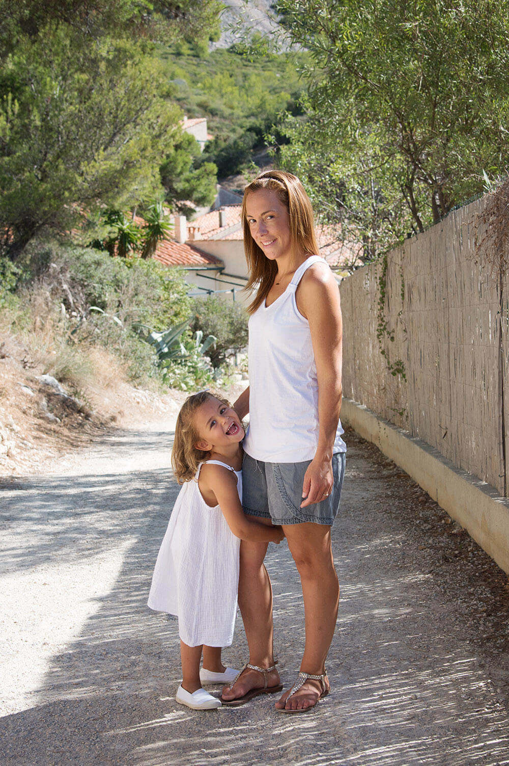 Photo en extérieur d'une maman et de sa fille qui lui tient la jambe. Séance photo à Sormiou.