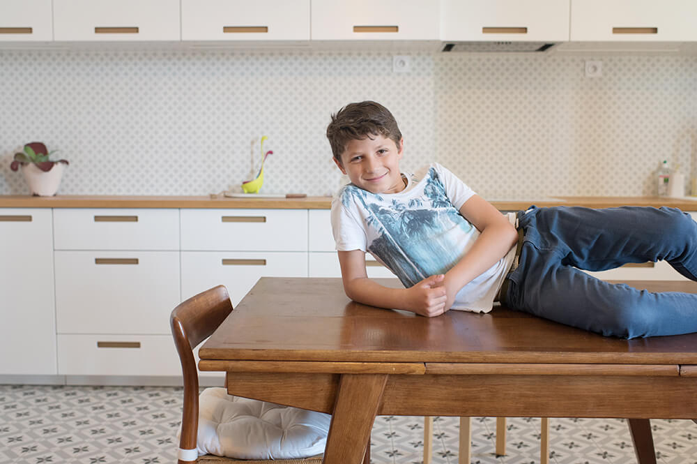 Portrait d'un adolescent allongé sur une table de cuisine.