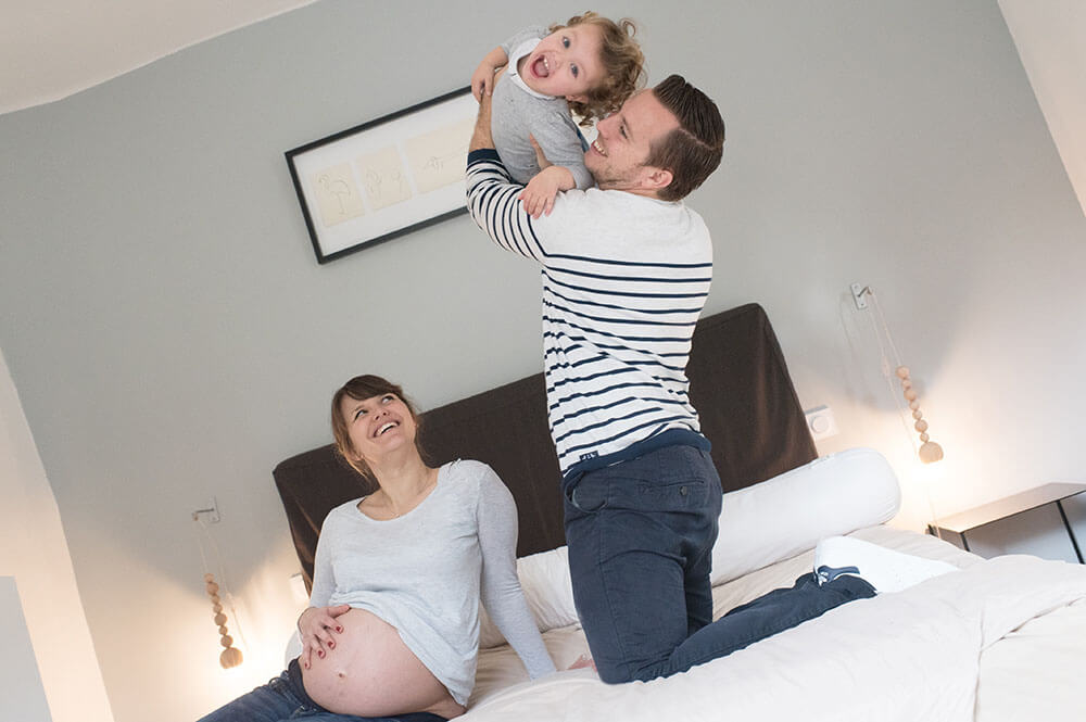 Papa qui joue avec sa petite fille sur son lit. 