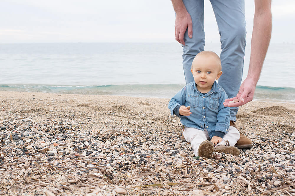 Enfant qui joue avec les cailloux de la plage.