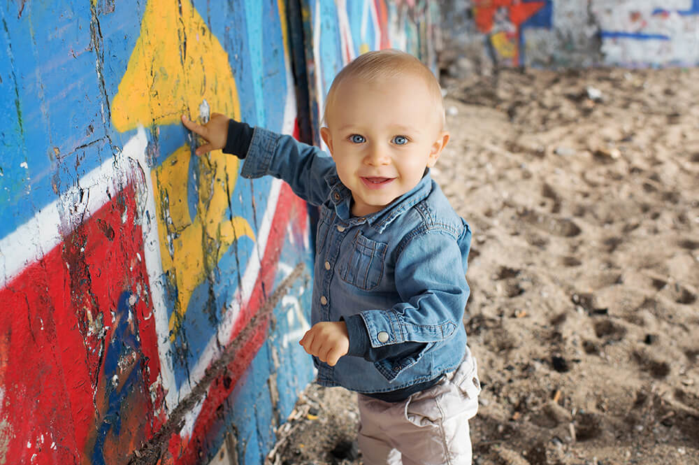 Portrait d'un tout petit devant des graffitis rouges.