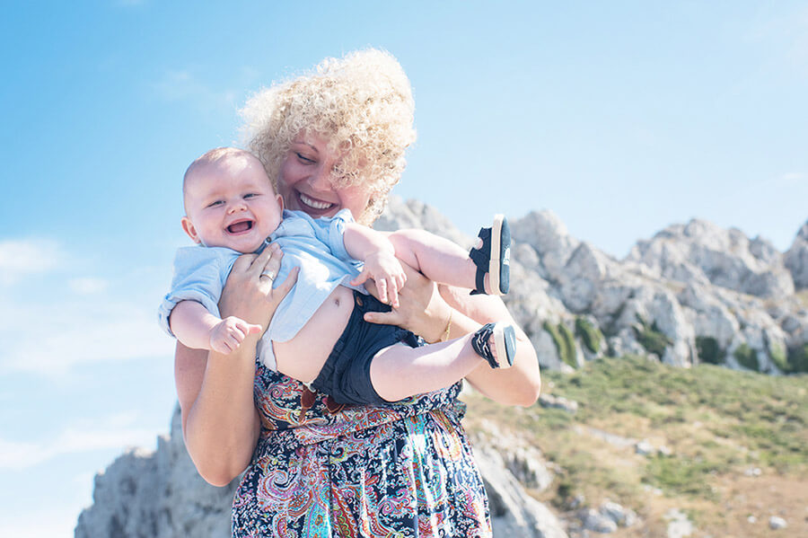 Portrait jouant avec son bébé avec un ciel bleu.