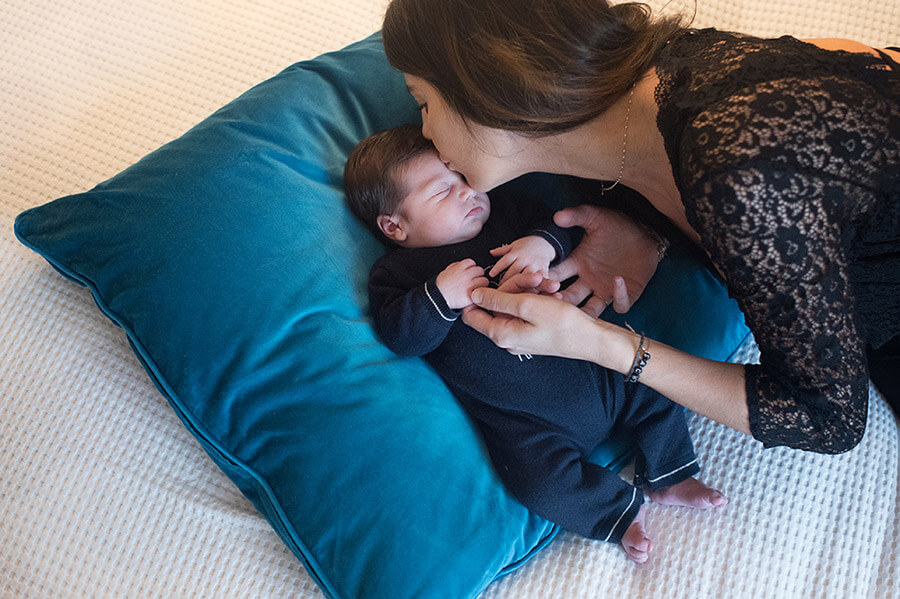 Maman faisant un bisou sur le front de son nouveau-né.