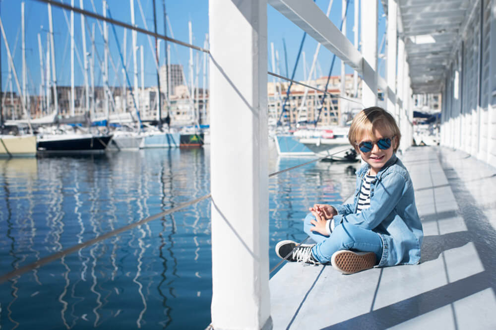 Portrait d'un enfant modèle avec uns superbe casquette Vans. Photo devant les voiliers du vieux-port à Marseille.