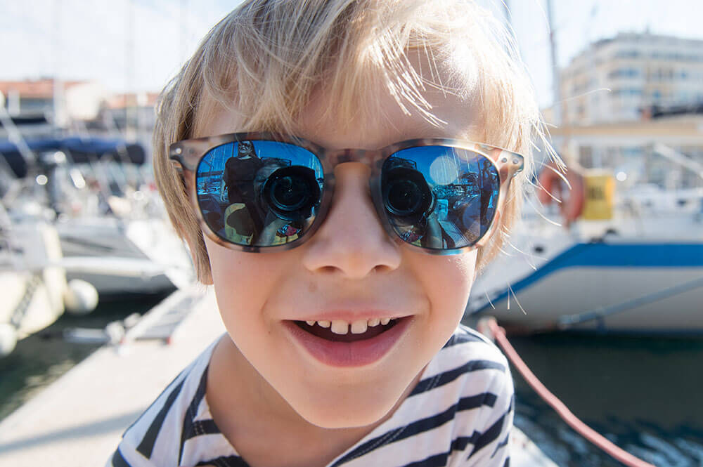 Portrait rapproché d'un enfant blond avec de grandes lunettes.