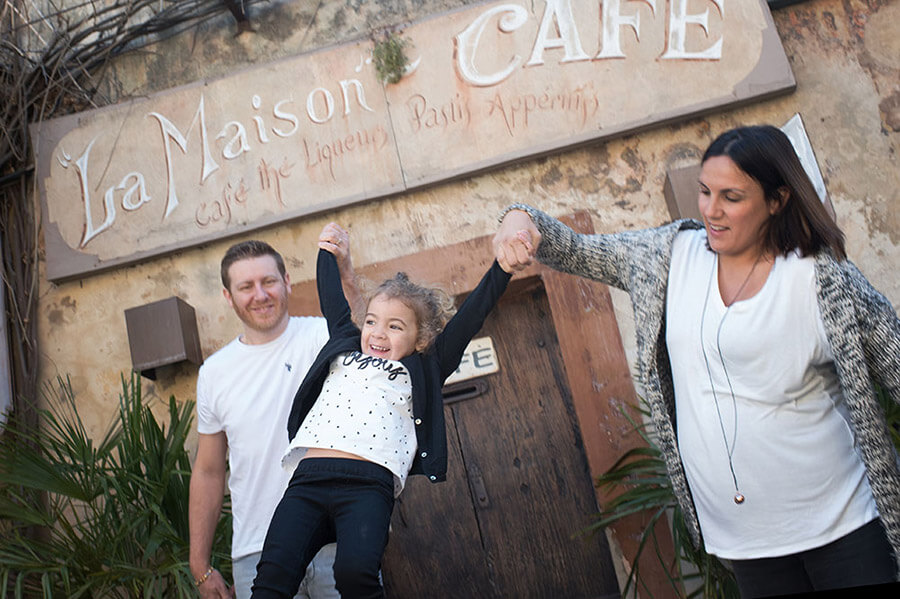 Parents jouant avec son enfant devant la maison du café à Lourmarin.