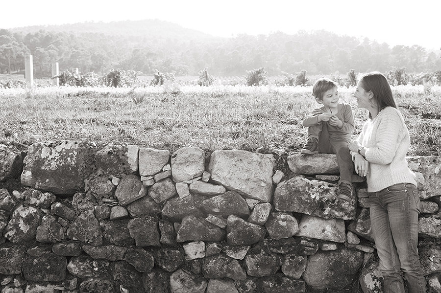 Photo en noir et blanc. Assis sur un mur en pierre.