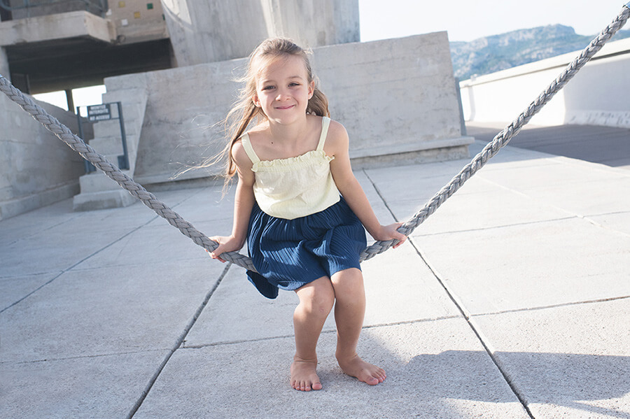 Portrait d'une enfant se balançant sur une corde balançoire.