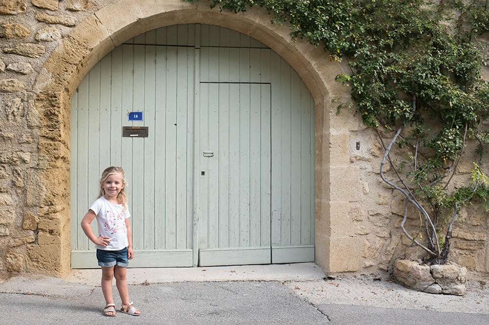 Séance photo famille Luberon. Demoiselle posant devant une jolie porte verte.