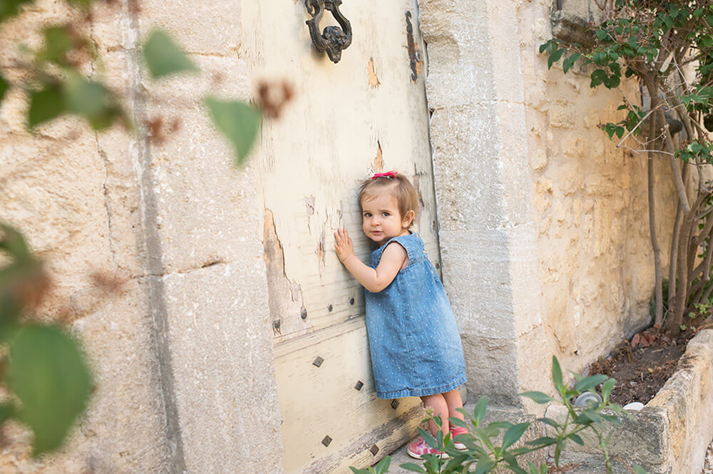 Enfant de un an se tenant debout devant une porte ancienne.