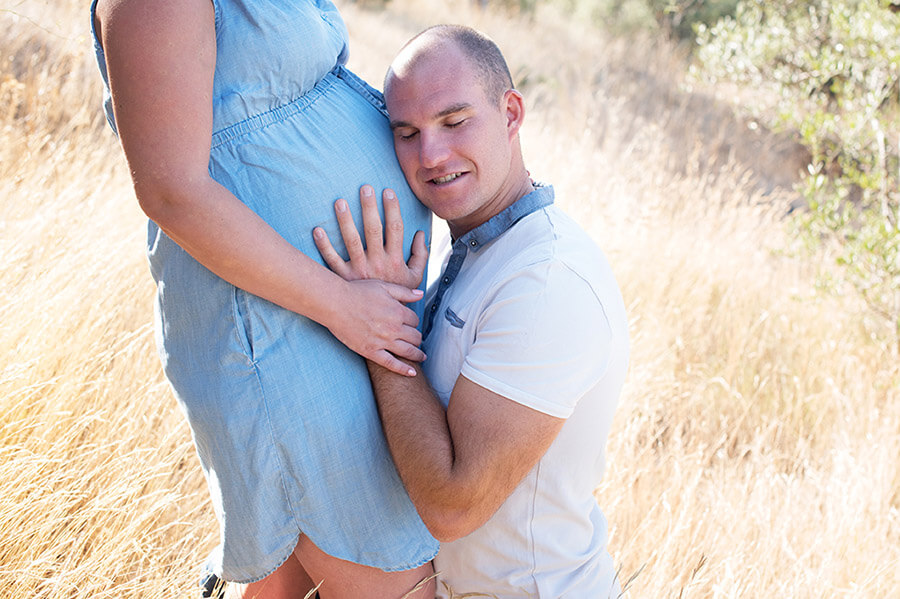 Futur papa écoutant son bébé dans le ventre de sa femme.