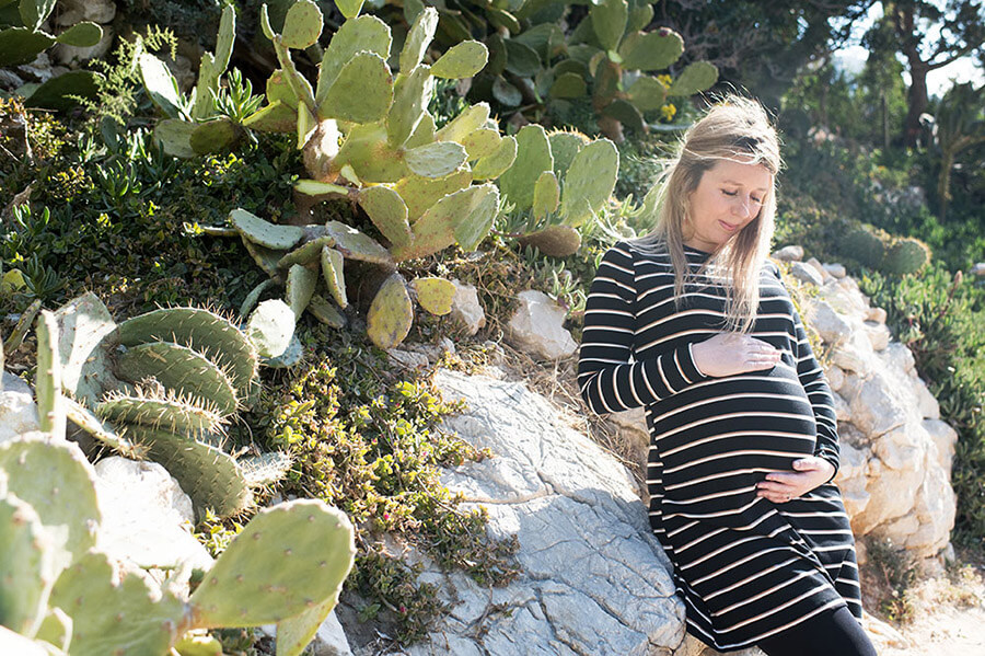 Portrait d'une femme enceinte devant des cactus.