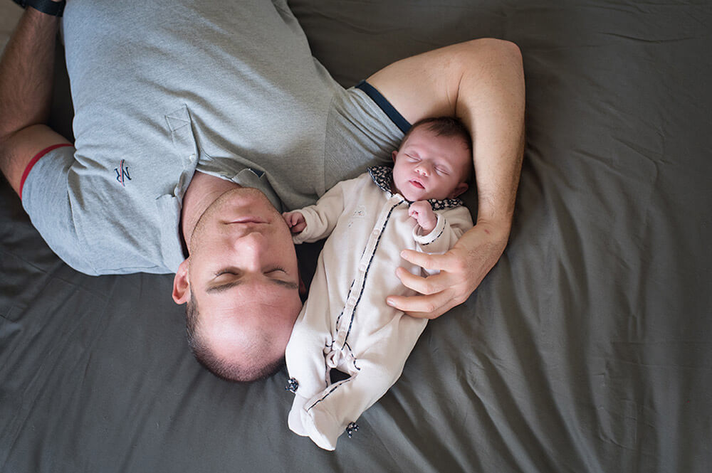 Photo originale d'un nouveau-né allongé sur le lit avec son papa.