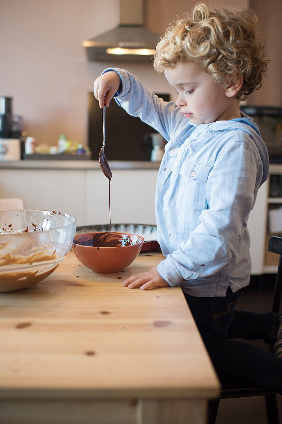 Portrait d'un petit blondinet entrain de jouer avec le chocolat fondu.