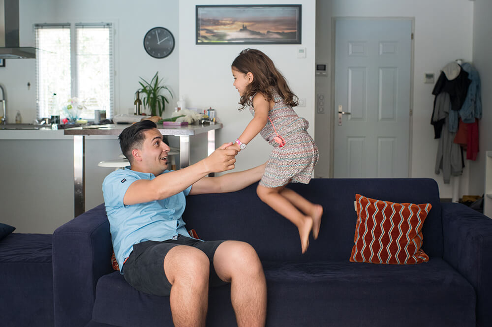 Jeune fille sautant sur le canapé avec son papa.