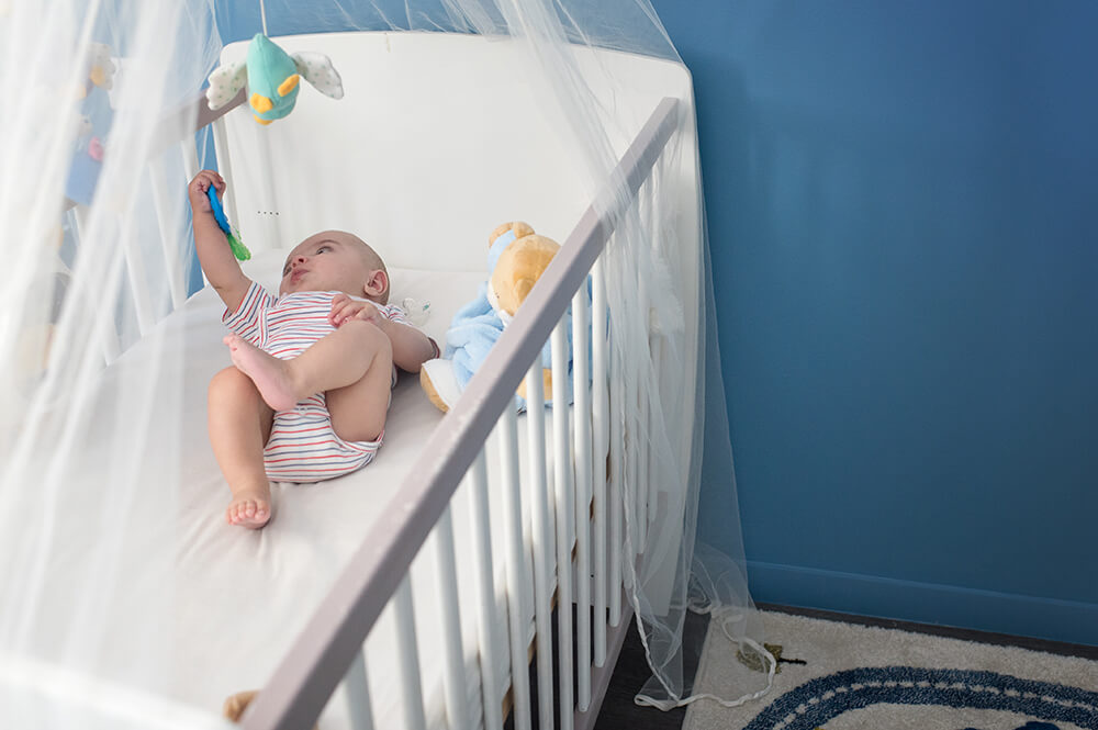 Bébé dans son lit jouant avec son mobile.