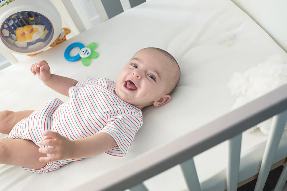 Bébé souriant dans son lit.