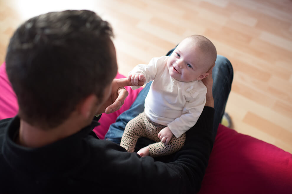 Bébé de quatre mois entrain de jouer avec son papa.