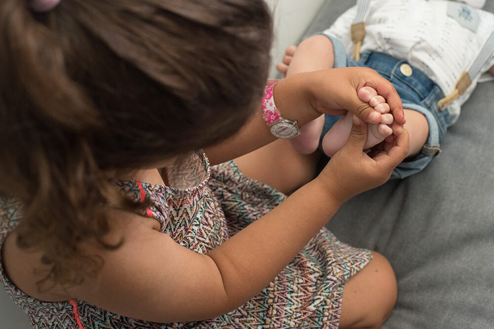 Bébé se faisant massé les petons par as grande sœur.