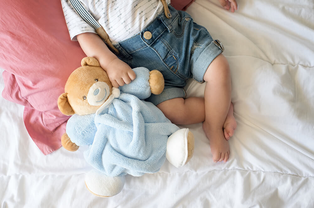 Bébé qui tient son doudou ours.