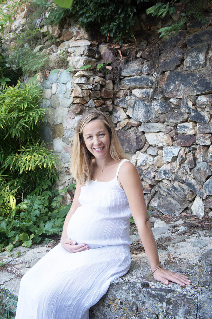 Portrait d'une femme enceinte dans une robe longue blanche.