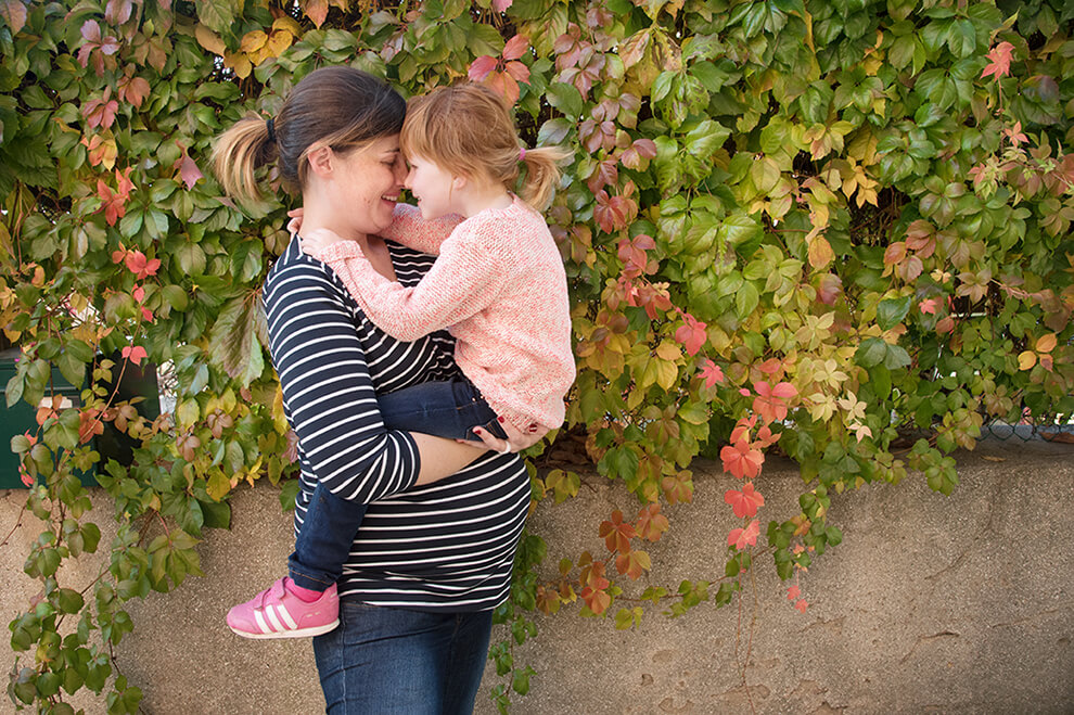 Fille assise sur le gros ventre de sa maman.