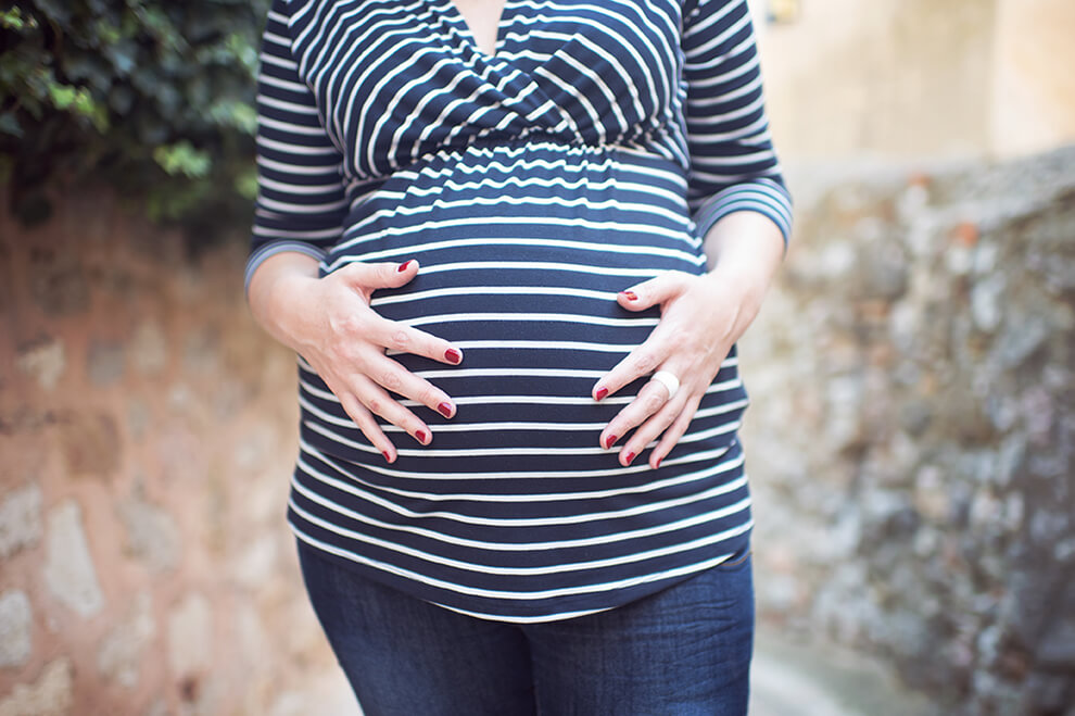 Cliché serré du gros ventre d'une femme enceinte en extérieur.