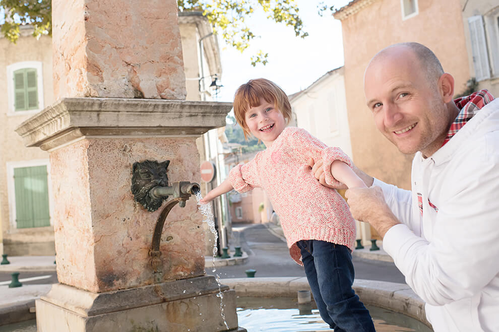 Portrait rigolo d'une jeune fille autour d'une fontaine.