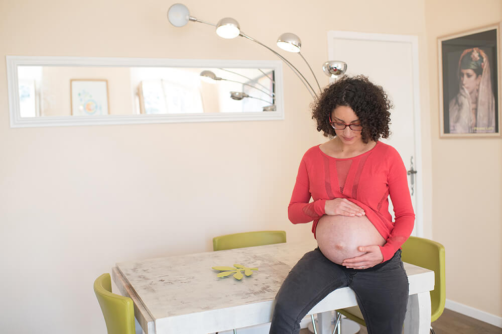 Jeune femme enceinte caressant son gros ventre.