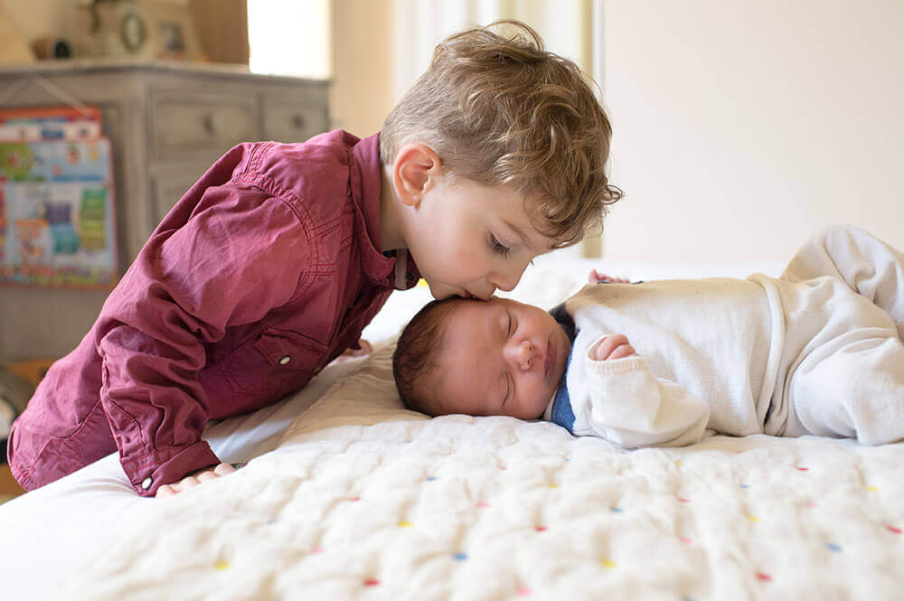 Le grand frère qui embrasse son tout petit frère.