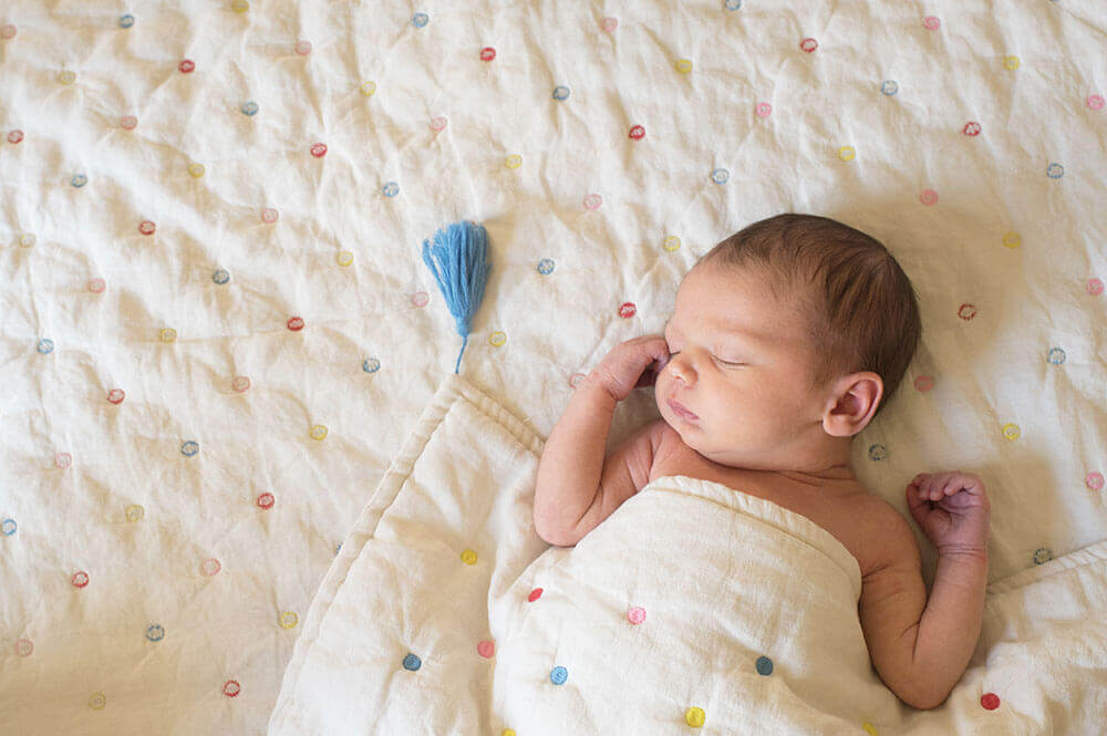 Nouveau-né enveloppé dans sa couverture et entrain de dormir.