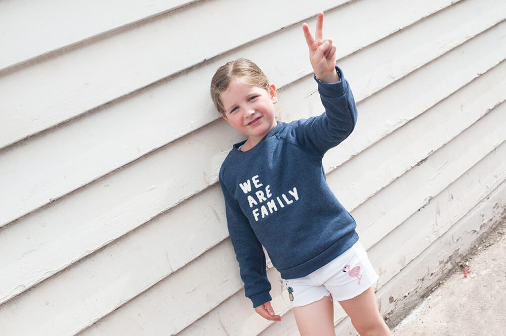 Portrait d'une jeune fille avec un pull We are family.