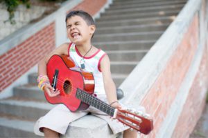 Portfolio enfant Marseille. Enfant entrain de jouer de la guitare.